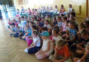 Grupa dzieci siedzi na podłodze.