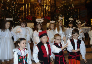 Dzieci stoją w kościele i spiewają.