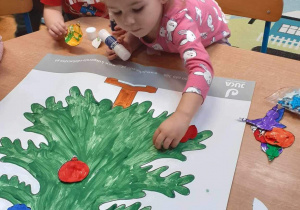 Chłopczyk i dziewczynka przyklejają na choinkę kolorowe bombki z papieu