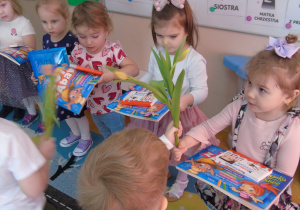 Chłopcy wręczają kwiaty i prezenty dziewczynkom z okazji Dnia Kobiet.