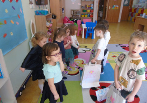 Chłopcy wręczają prezenty dziewczynkom z okazji Dnia Kobiet.