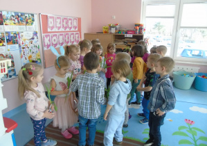 Chłopcy wręczają kwiaty i prezenty dziewczynkom z okazji Dnia Kobiet.