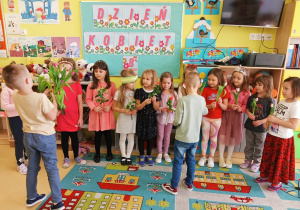 Chłopcy wręczają kwiaty i prezenty dziewczynkom z okazji Dnia Kobiet.