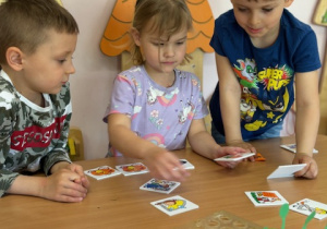 dwóch chłopców i dziewczynka siedzą przy stoliku wspólnie układają obrazki