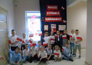 Dzieci trzymają w rękach flagę Polski i pozują do zdjęcia.