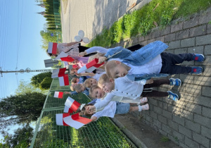 Dzieci idą na spacer. W rękach trzymają flagę Polski.