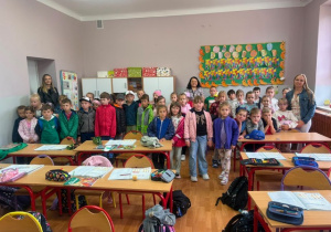 Grupa przedszkolaków wraz z opiekunkami w sali lekcyjnej.