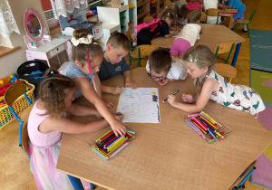 Przedszkolaki rysujące przy stoliku.